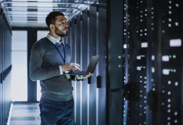 ittechnicianworksonlaptopnexttoaservercabinet